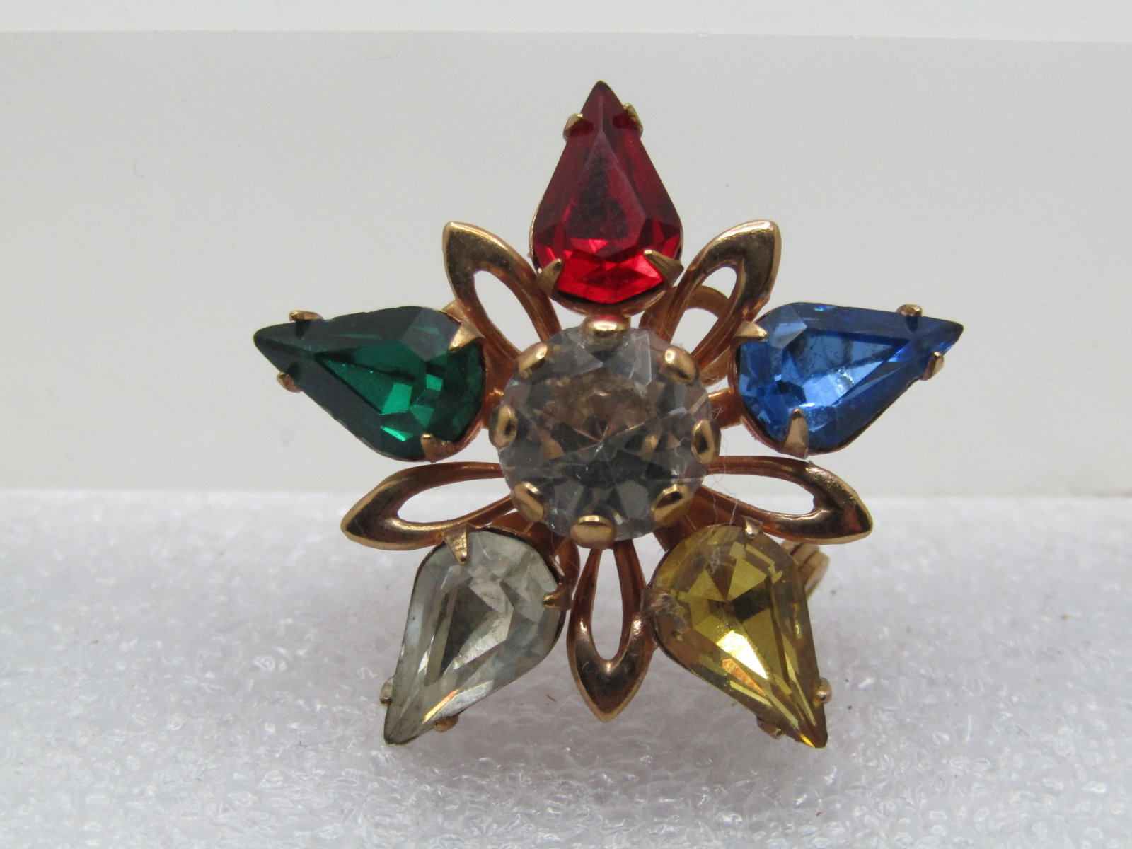 Vintage Gemtone Rhinestone Brooch, 1960's: Vintage Gemtone Rhinestone Brooch, 1960's. Gold tone and appx. 1.25" across. 8.5mm center stone and appx. 9mm by 6mm pear-shaped star points in yellow; clear; red; green; yellow; and, blue. There are