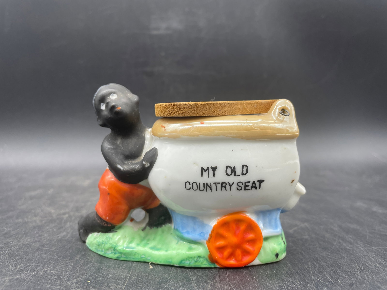 BLACK AMERICANA CIGARETTE ASHTRAY BOY PUSHING TOILET MY OLD COUNTRY SEAT: Title: BLACK AMERICANA CIGARETTE ASHTRAY BOY PUSHING TOILET MY OLD COUNTRY SEAT Date/Period: approx 1930's Dimension: NA Material: porcelain ceramic Additional Information: This is a nice vintage Blac