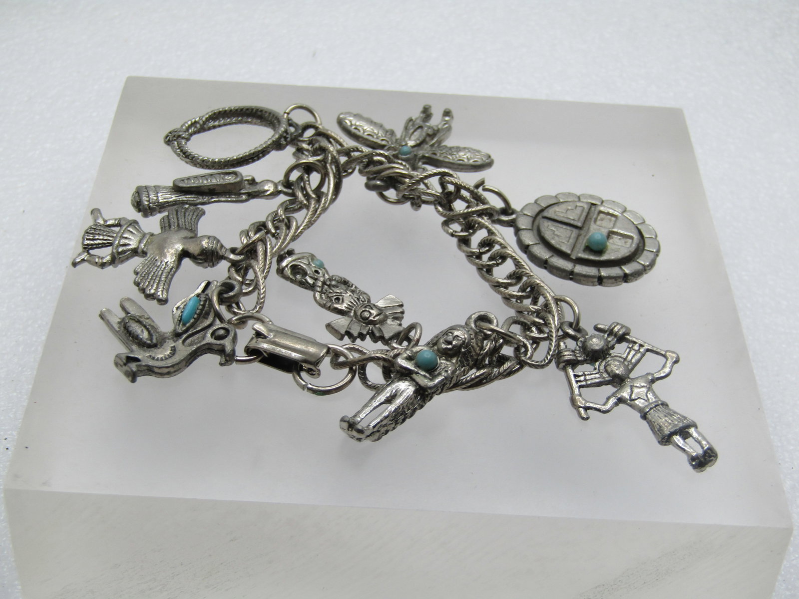 Vintage Southwestern Native American Charm Bracelet, 7.5", 1960's: Vintage Southwestern Native American Charm Bracelet, 7.5", 1960's. Silver tone. This has a textured double link and appx. 6.5mm wide, flip clasp. It has nine charms in the Native American theme, bird,