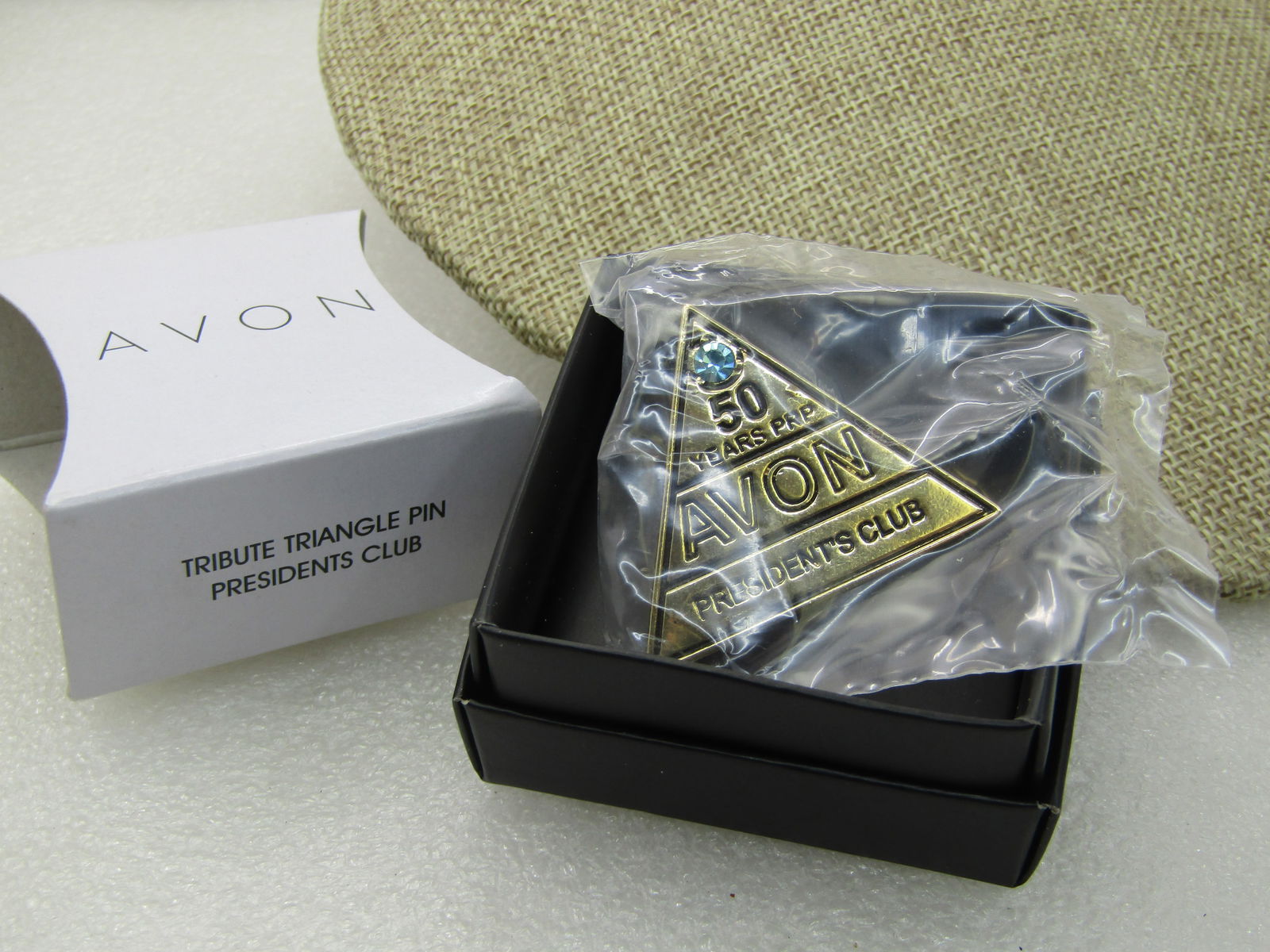 Avon 50 year President's Club, In Box: Avon 50 year President's Club, In Box. Blue cut stone in top of pyramid shape with 50 years PRP, AVON Presidents CluB written on the gold tone Pin, with paperwork, original box and sleeve. Never opene