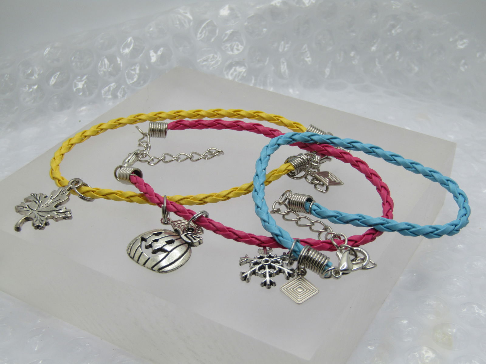 3 Braided Seasonal Charm Bracelets, 7.5"-9.5": 3 Braided Seasonal Charm Bracelets, 7.5"-9,.5". Braded bracelts - pink has a pumpkin charm; the bue has a snowflake; and the yellow is a leaf. They are 7.5" with a lobster clasp and 2" extender chain.