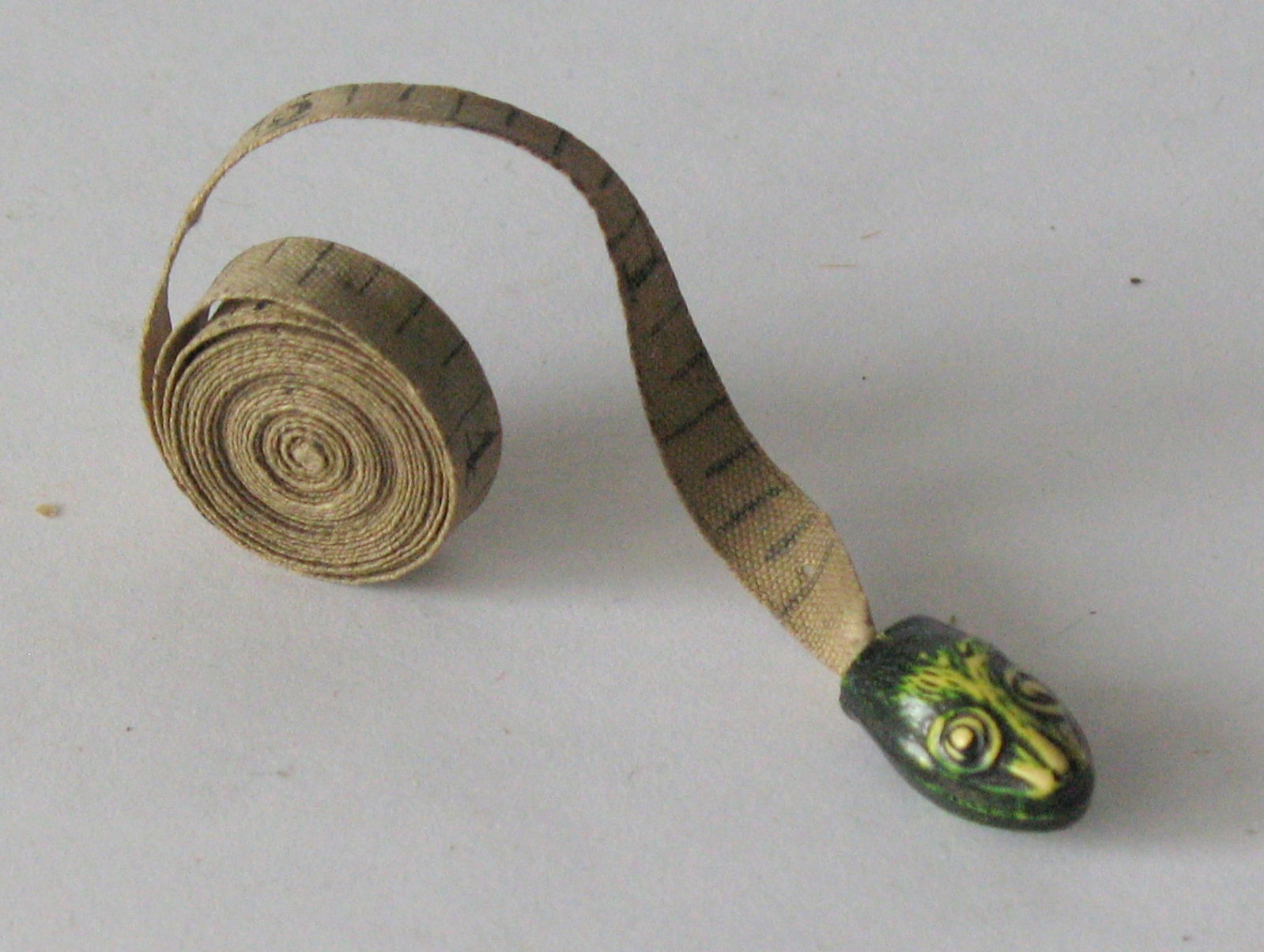 Antique cast metal snake head sewing tape measure.: Title: Antique cast metal snake head sewing tape measure. Date/Period: 1920's Dimension: 36” long snake head 3/4” Additional Information: Nice antique cast metal snake head sewing tape mea