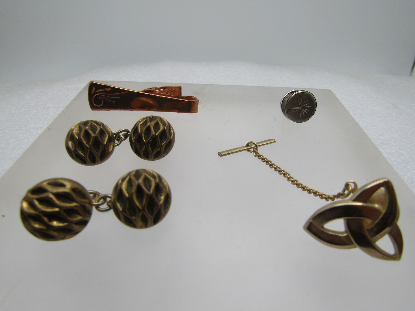 Vintage 4 Pc. Cuff Link, Tie Tack & Bar Lot, 1940's-1960's: Vintage 4 Pc. Cuff Link, Tie Tack & Bar Lot, 1940's-1960's. Copper 1.5" Tie clasp 1950's. 1/3" wide at end with a swirled design. Celtic triquetra symbol tack pin with chain/bar. Gold tone and appx. 3