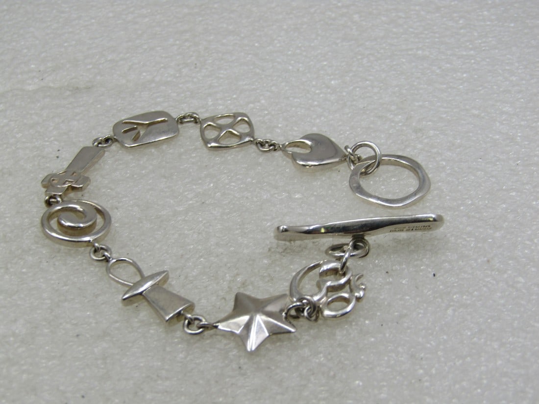 Sterling Cross, Peace Sign, Star Bracelet, RLM Studio, 7": Sterling Cross, Peace Sign, Star Bracelet, RLM Studio (Robert Lee Morris) , 7", appx. 18.11 grams. Mixed links with hearts, cross, compass points, OM, peace sign, ankh-like symbol, star and other symb