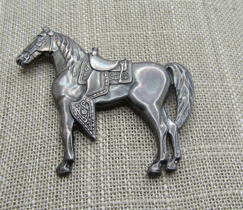 Vintage Sterling Horse with Western Saddle Brooch, 1960's: DescriptionVintage Sterling Horse with Western Saddle Brooch, 1960's. This is a brooch that is marked sterling and tested with a weight of appx. 9.05 gr. It is 2" wide and 1.75" tall. It is in very go