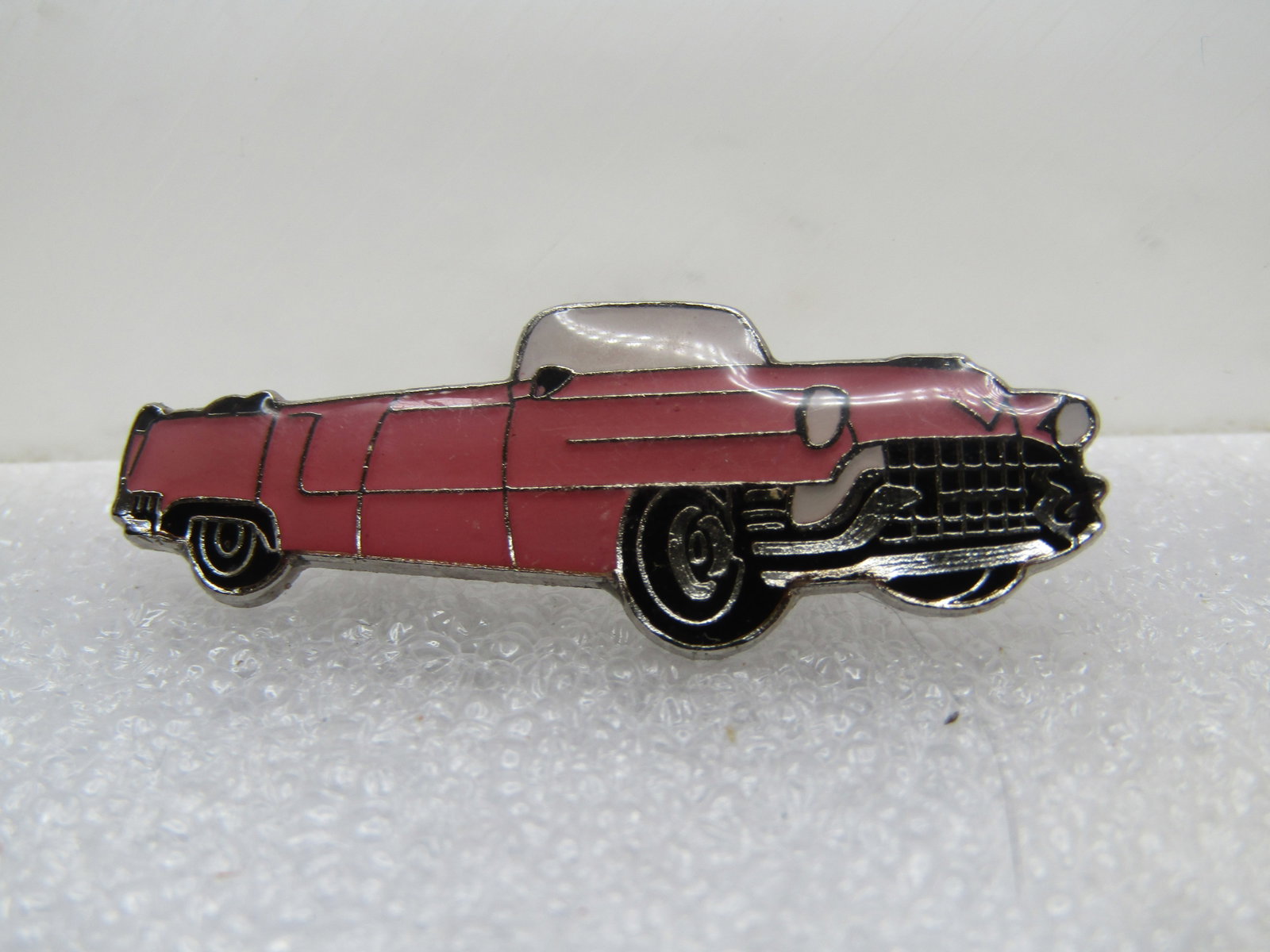Vintage Pink Cadillac Enameled Brooch, 1980's-1990's: Vintage Pink Cadillac Enameled Brooch, 1980's-1990's. Silver tone with locking clasp. Pink convertible cadillack with black enameled tires and accents. It is appx. 1.5" wide and 1/2" tall. It is not s