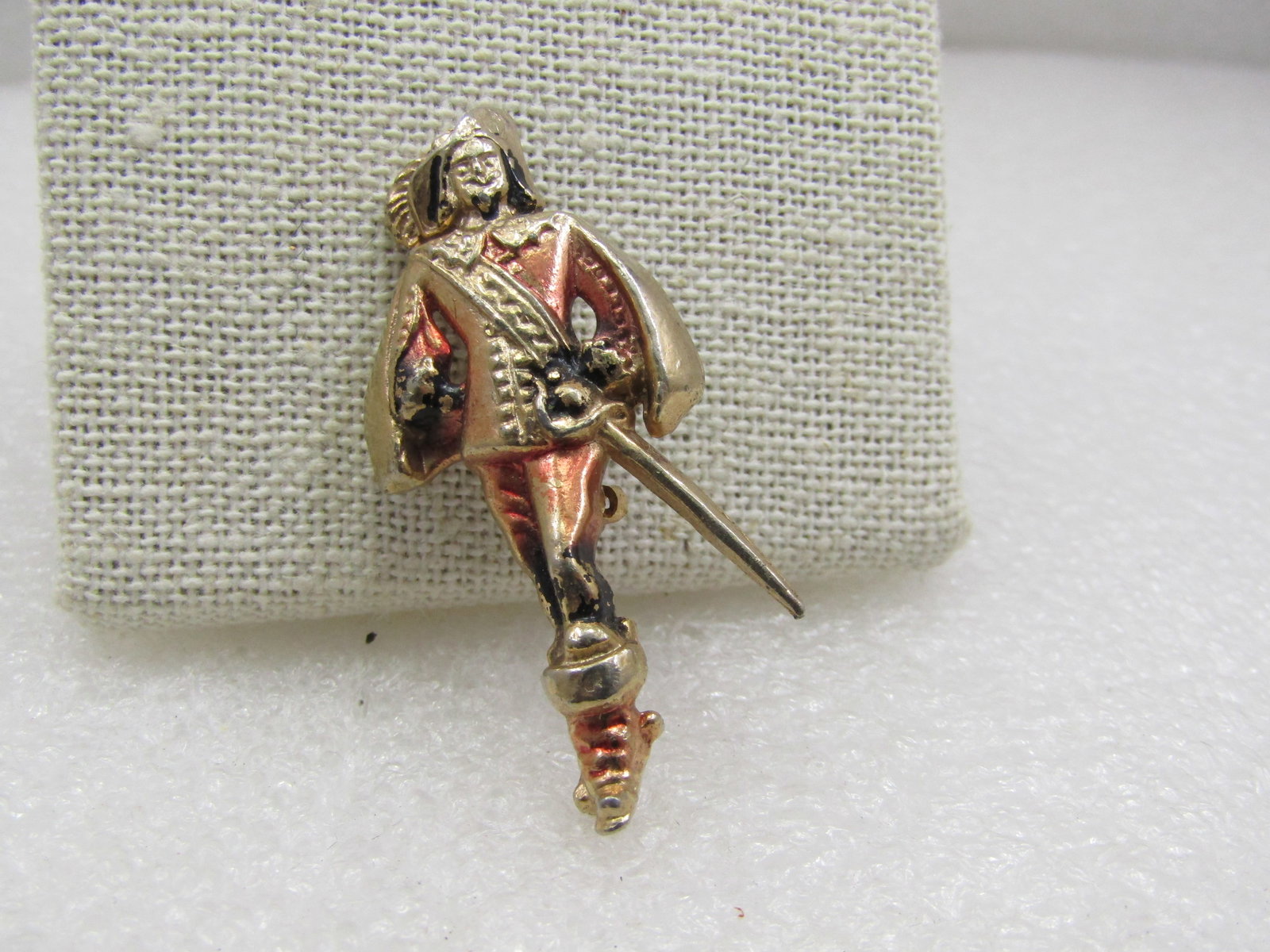 Vintage Enameled Muskateer Brooch, Gold Tone, 1960's, 1.25": Vintage Enameled Muskateer Brooch, Gold Tone, 1960's, 1.25" tall and 1" wide. Enameled with a light red wash over the muskateer's pants, boots and inside of his cape. Gold tone. Not signed by the make
