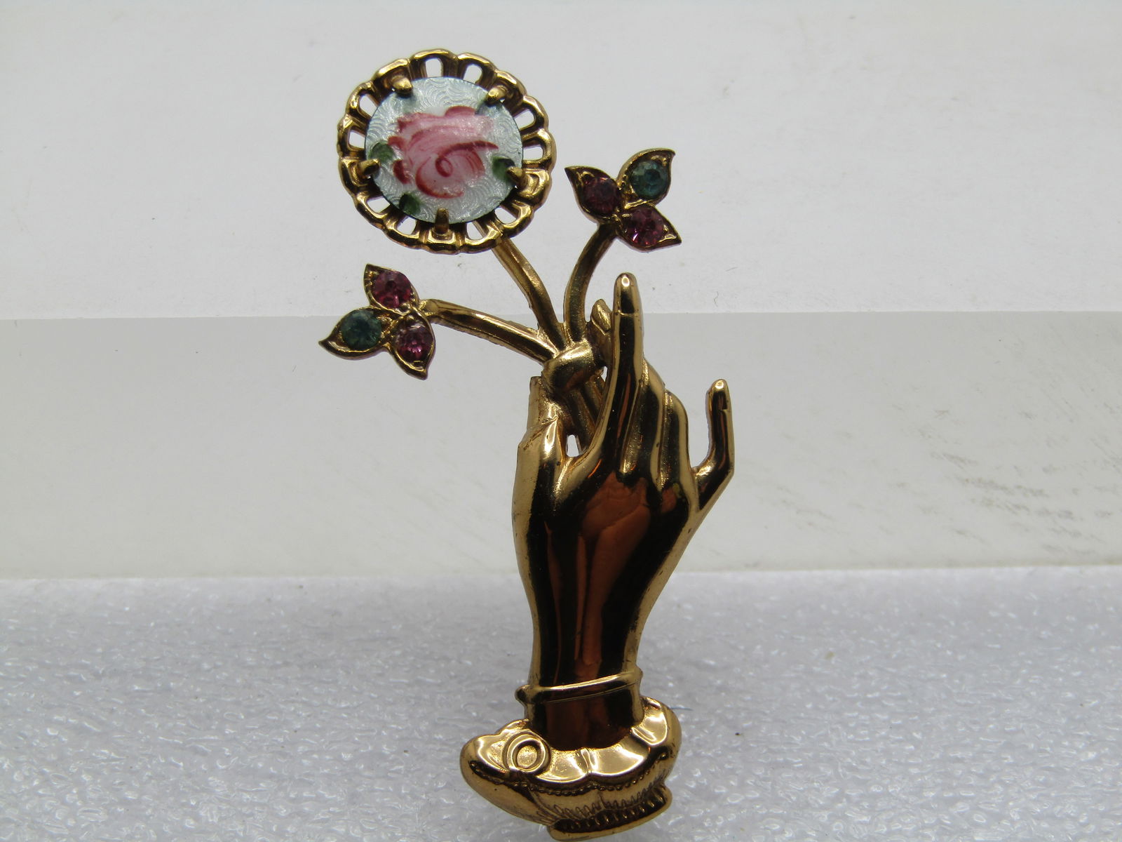 Vintage Guilloche Rose Hand Brooch, Rhinestones, 1960's, Coro: Vintage Guilloche Rose Hand Brooch, Rhinestones, 1960's, Coro. The hand is pointing upward holding a stem with the lower to stems having pink and blue rhinestones setin leaves and the larger - a round