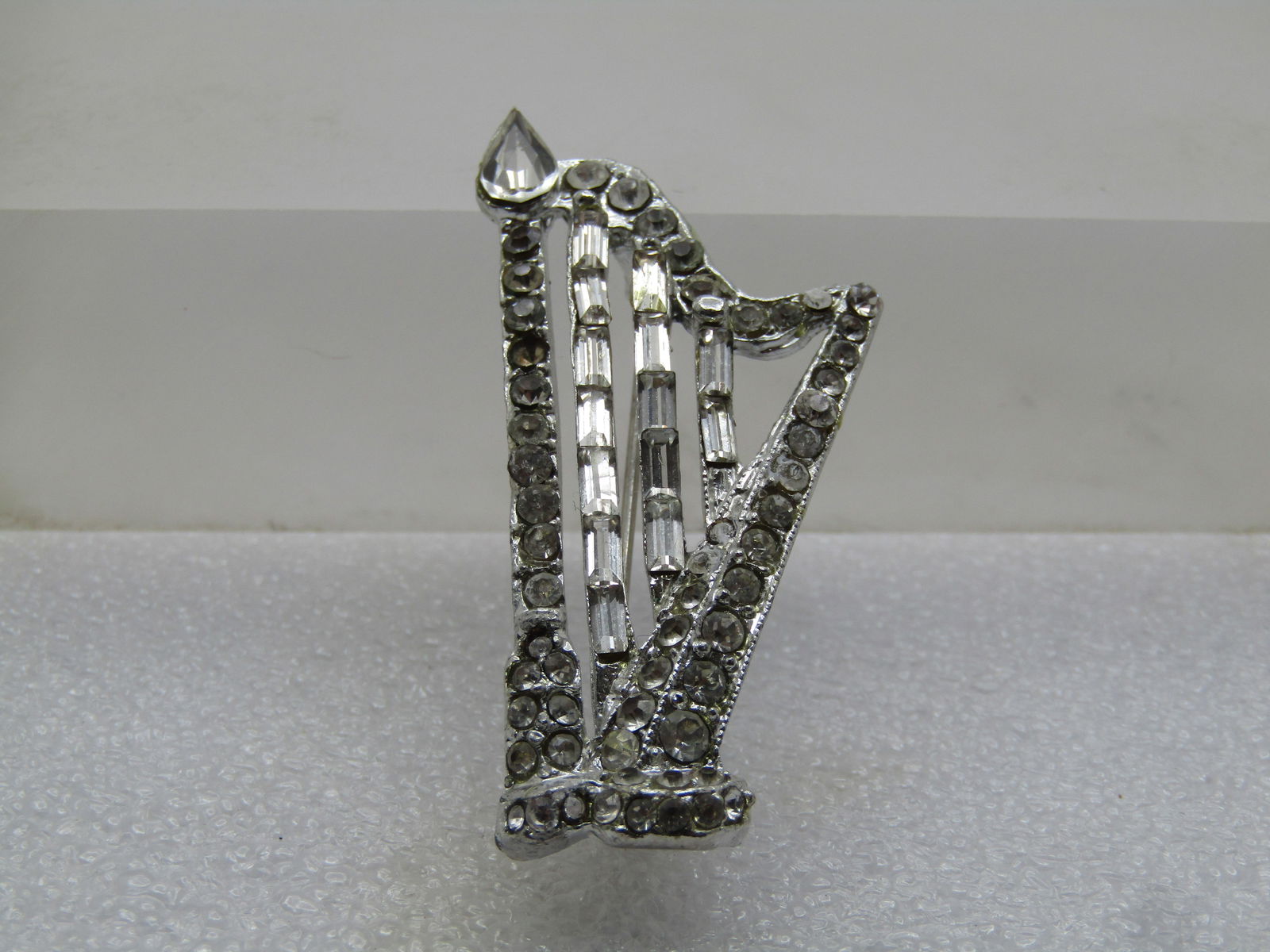 Vintage Rhinestone Harp Brooch, 1940's-1950's: Vintage Rhinestone Harp Brooch, 1940's-1950's. Clear rhinestone baguettes on the stringed portion of the harp with round rhinestones in the frame and a single pear-shaped on the top. It is appx. 2" ta