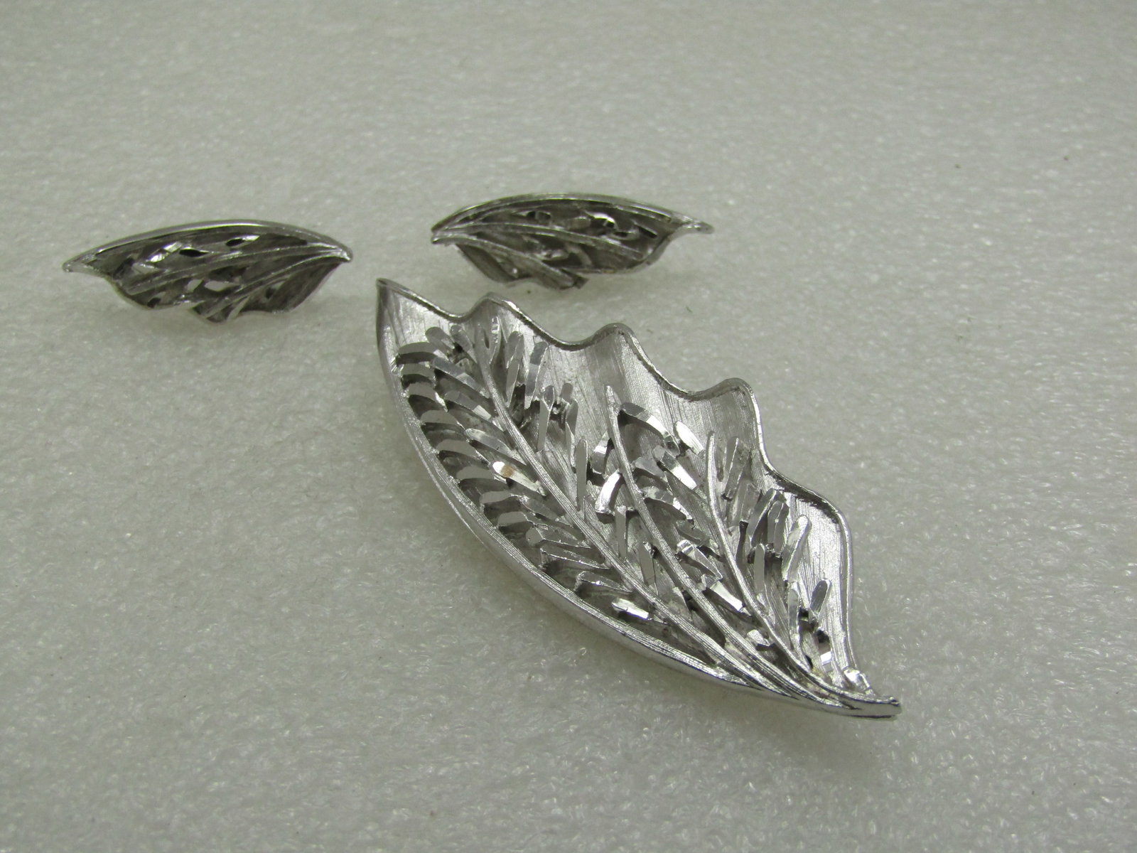 Vintage Coro Leaf Brooch & Clip Earrings Set, Tiered, 1960's: Vintage Coro Leaf Brooch & Clip Earrings Set, Tiered, 1960's. Silver tone with a wavy bottom layer that is larger than a shiny stem leaf design over the background. The brooch is 3.25" tall and appx.
