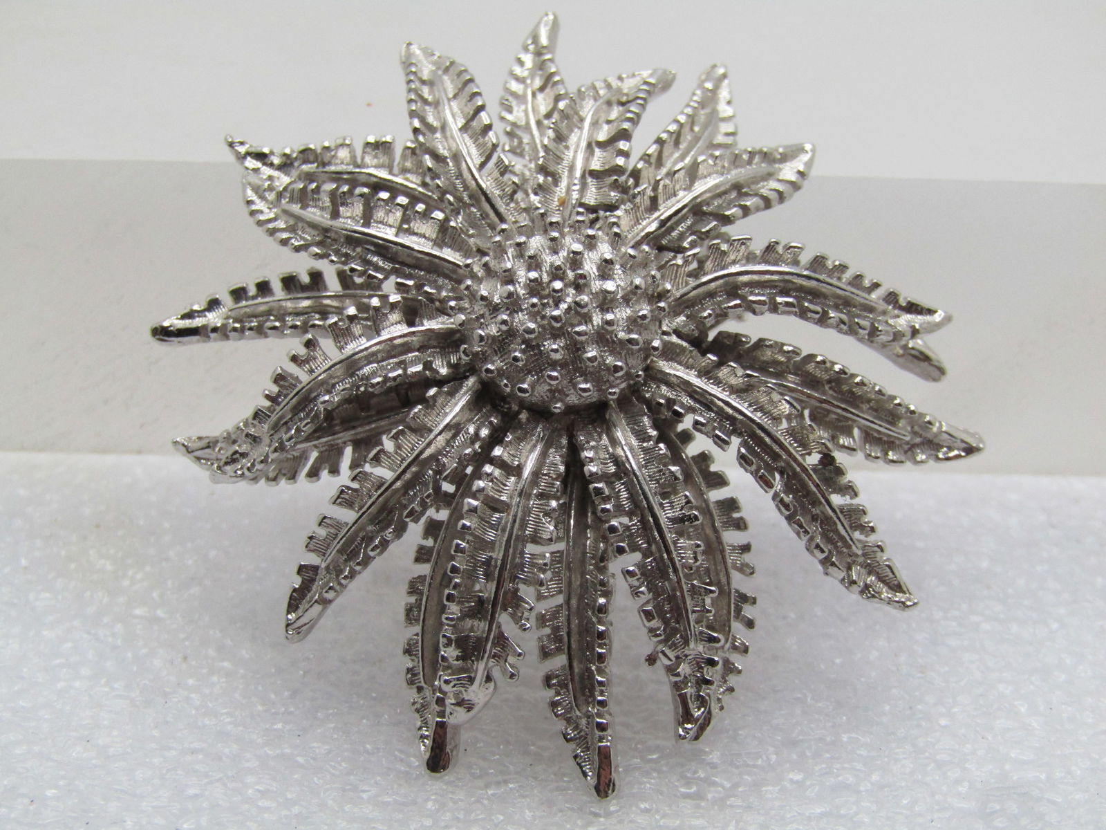 Vintage Coro Blossom Brooch, Tiered, 1960's: Vintage Coro Blossom Brooch, Tiered, 1960's, Silver tone with smooth and textured finish with the fern-like petals reaching downward and a round cetner with raised smooth dots. It is appx. 2" wide. It