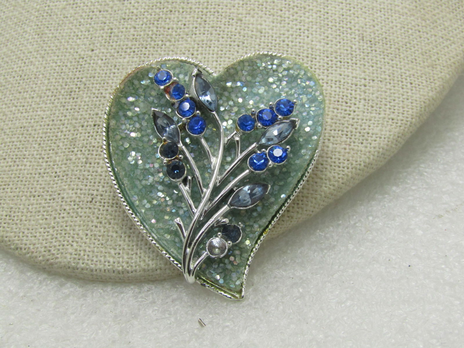 Vintage Coro Glitter & Rhinestone Heart Brooch, Mid-Century, 2": Vintage Coro Glitter & Rhinestone Heart Brooch, Mid-Century, 2" tall and 1.5" wide. Offset heart design with a background of seafoam heavy glitter - and a floral stem over top with marquise and round