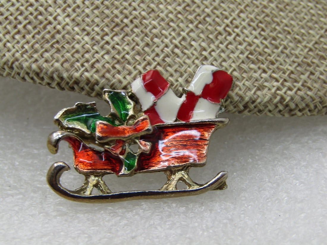 Vintage Enameled Christmas Sleigh Brooch, 1950's-1960's: Vintage Enameled Christmas Sleigh Brooch, 1950's-1960's. Red, Green, White enameling with packages and holly and berries. Not signed by the maker. 1.25" wide and 1" tall. Very good vintage condition. 