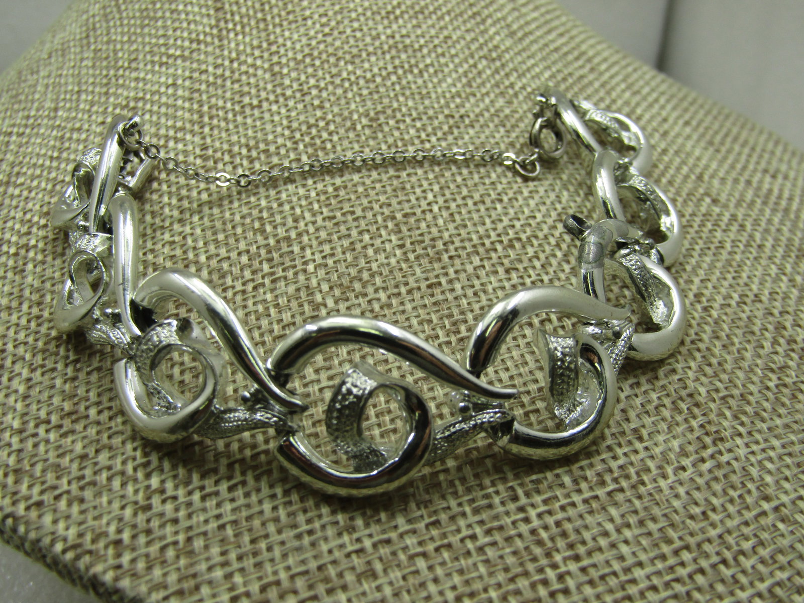 Vintage Coro Silver tone Curved Link Bracelet, Safety Chain, 7", 1960's.: Vintage Coro Silver tone Curved Link Bracelet, Safety Chain, 7", 1960's.. 3/4" wide. This has a tectured curl in the center of the link - wave-like. Silver tone. Safety chain connected by a loop at ea