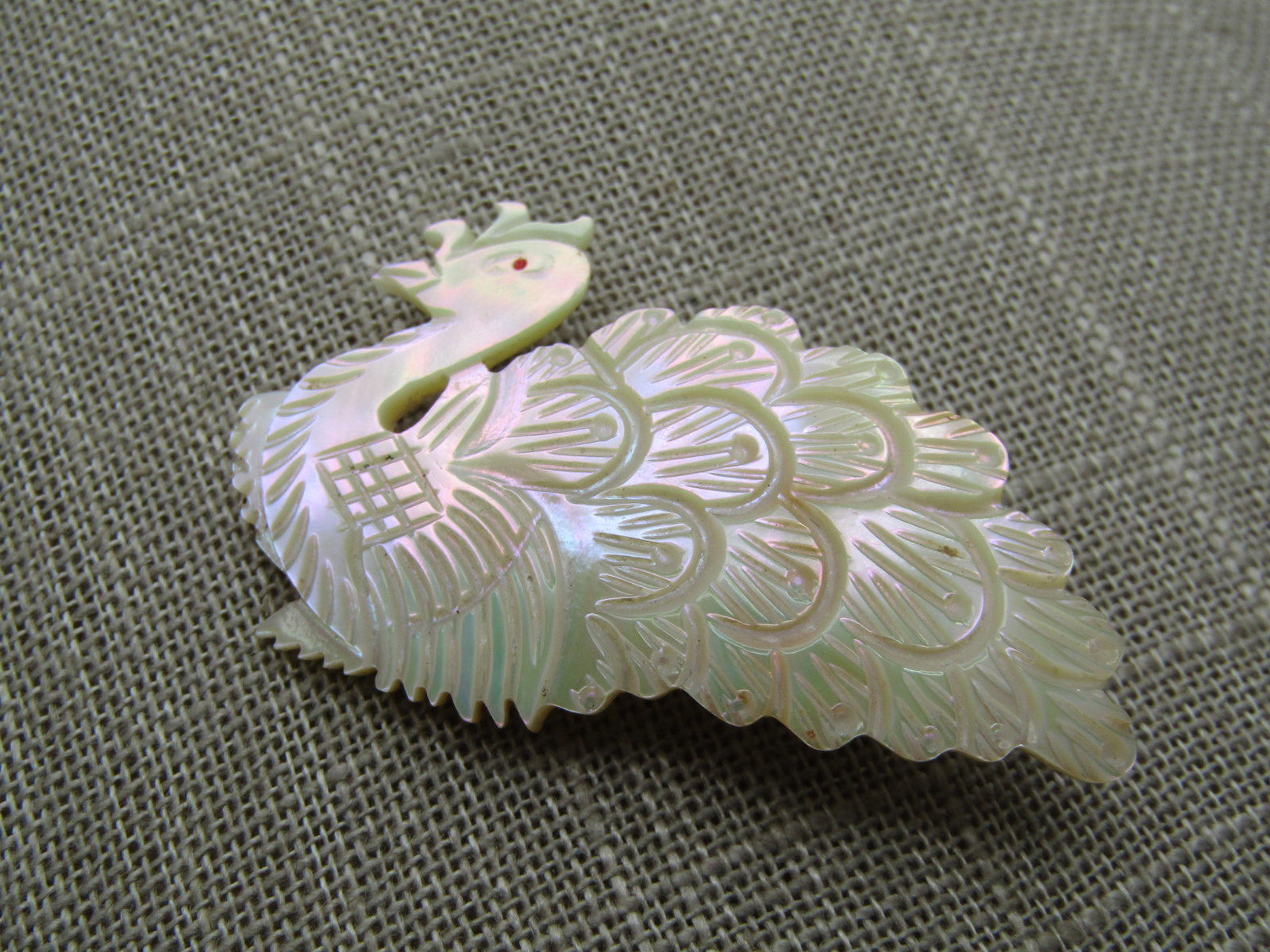 Vintage Carved MOP Peacock Brooch, 1960's-1970's, 2-1/8": Vintage Carved MOP Peacock Brooch, 1960's-1970's, 2-1/8" wide and 1.25" tall. Red enameled eye with caved feathers. The peacock is in a crouched sitting position. It is in very good conidtion other th