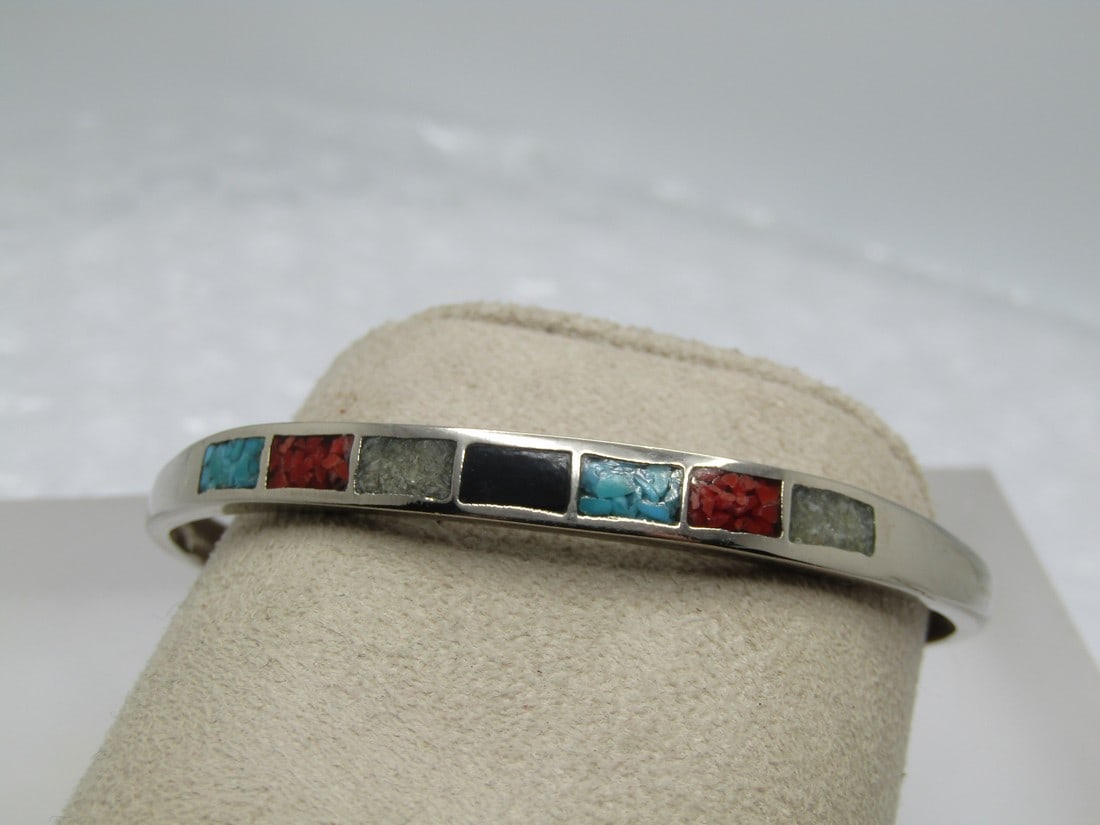 Vintage Costume Southwestern Inlaid Cuff Bracelet, 7": Vintage Costume Southwestern Inlaid Cuff Bracelet, 7". The bracelet has inlaid faux turquoise, coral, mother-of-pearl chips and faux onyx. Thre are seven sections across the top of the bracelet. The b