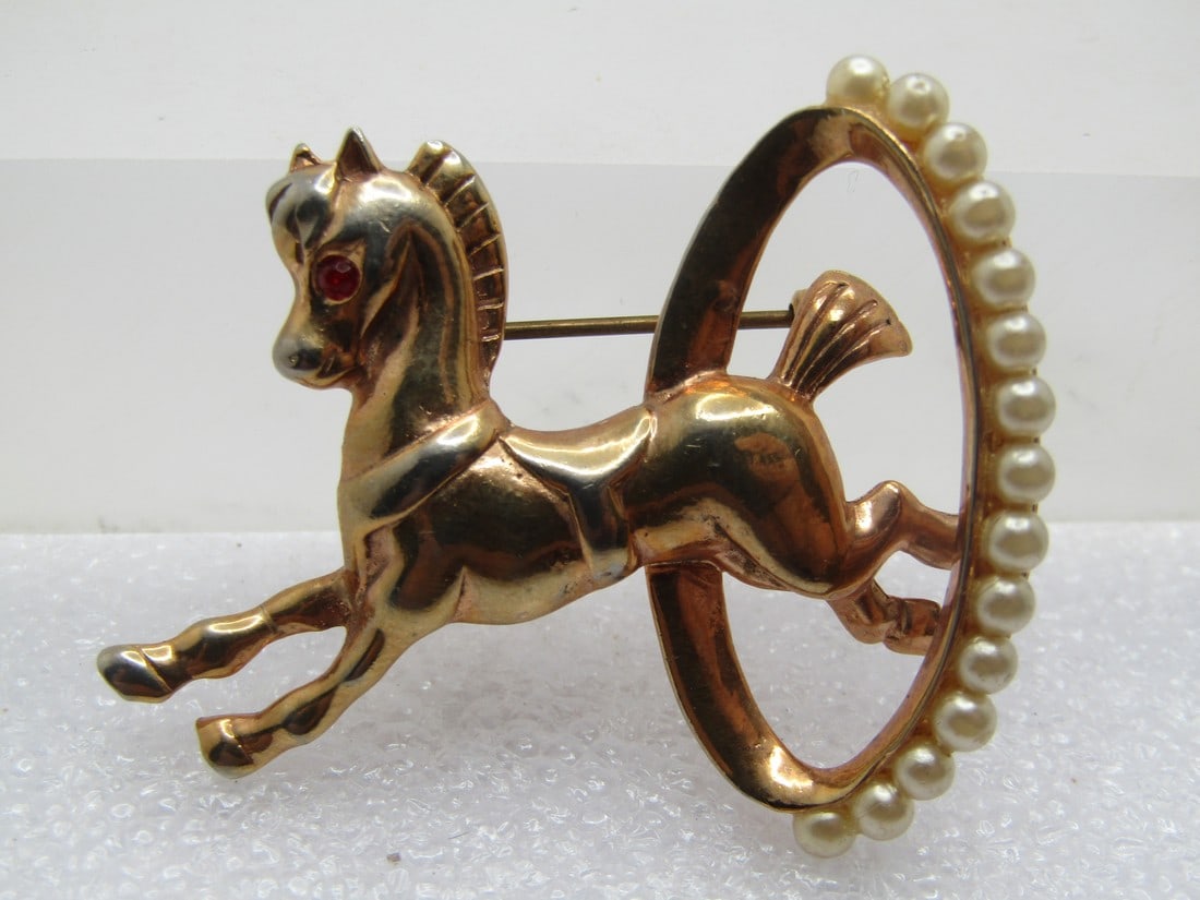 Vintage Horse Jumping Through Ring Brooch, 1950's-1960's: Vintage Horse Jumping Through Ring Brooch, 1950's-1960's. Faux Pearls and red rhinestone eye. Gold tone and appx. 1.75" tall and 1.5" wide. It is not signed by the maker. Very good condition. (W9223.4