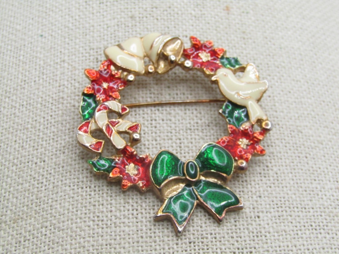 Vintage Enameled Christmas Brooch, 2": Vintage Enameled Christmas Brooch, 2" with white bells and dove, candy canes, poinsettias, and a green bow. Gold tone. Not signed or marked. Age is appx. 1980's-1990's. Very good condition. (W111222.4