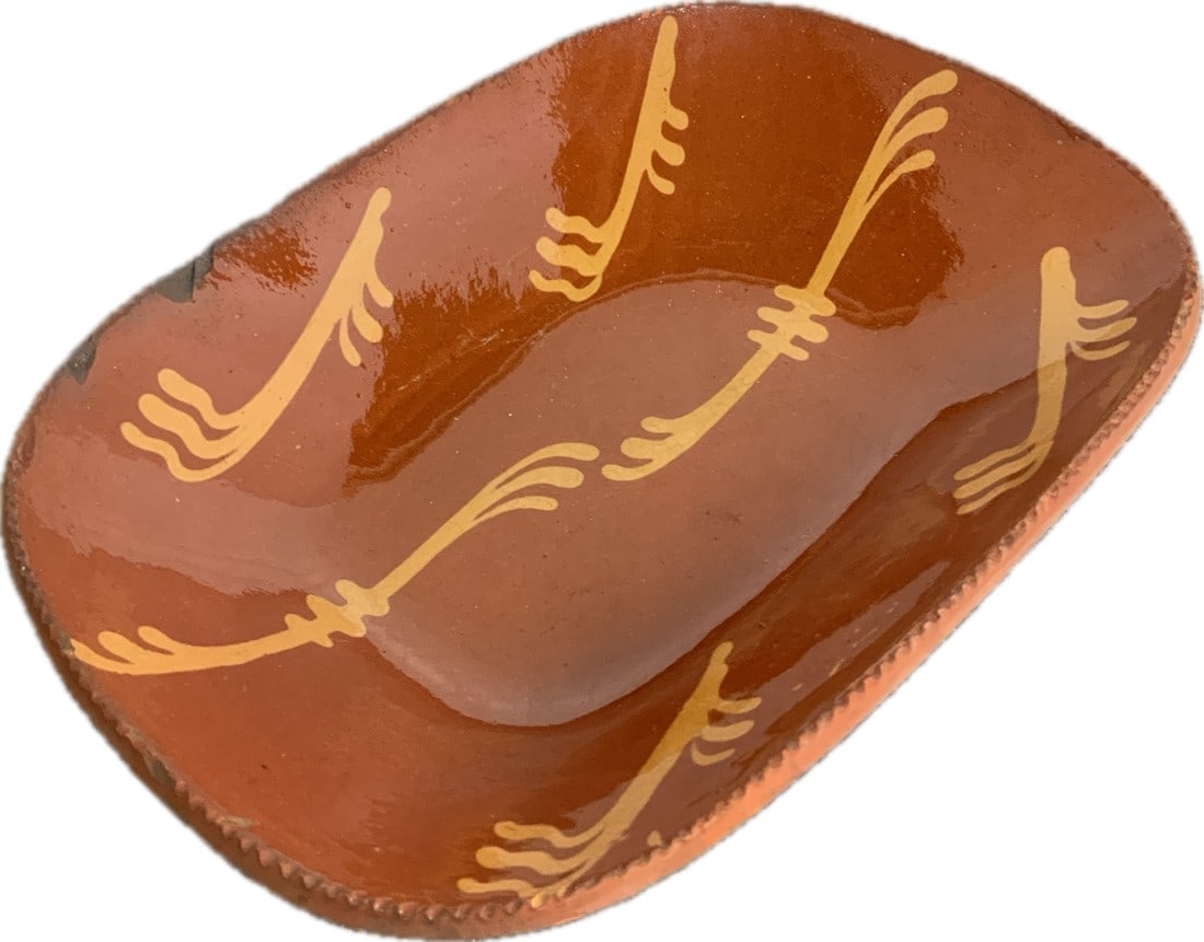 Pennsylvania Redware Loaf Dish: Slip-Decorated Redware Loaf Dish, Philadelphia, PA Origin, Second Quarter 19th Century, Oval Dish with Coggled Edge, The Lead-Glazed Interior Decorated with Six Stylized Trails of Yellow Slip. Rim Chi