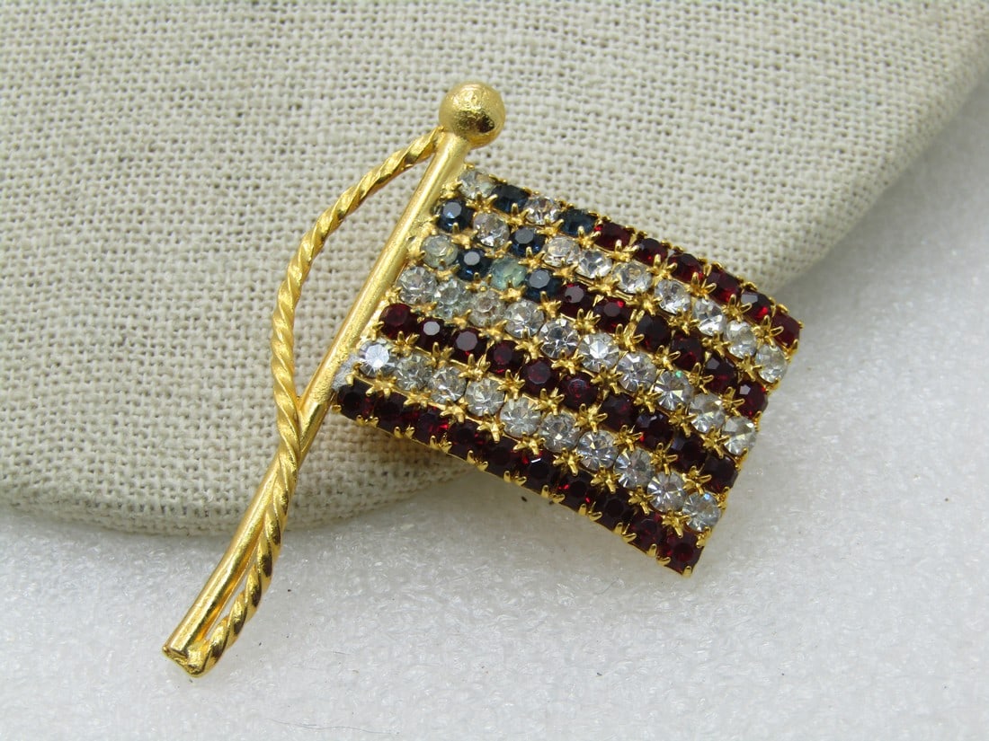 Vintage Blue & Clear Rhinestone USA Flag, Gold Tone, 2": Vintage Blue & Clear Rhinestone USA Flag, Gold Tone, 2" by 1.5". Flag pole with rope, 1970's-1980's. Very good condition. Not signed by the maker. (INV. W.2720.15.7 SS2676 LET LD 10/11/20) Reserve: $2