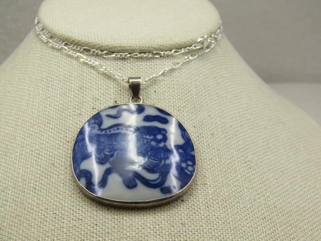 Vintage Sterling Chinese Dragon Pottery Pendant on 20" Figaro Chain: Vintage Sterling Dragon Pottery Pendant on 20" Figaro Chain. The pendant is domed and in blue and white pottery that is appx. 2" tall with swing bail and 1-5/8" wide. It has the Chinese dragon as the 
