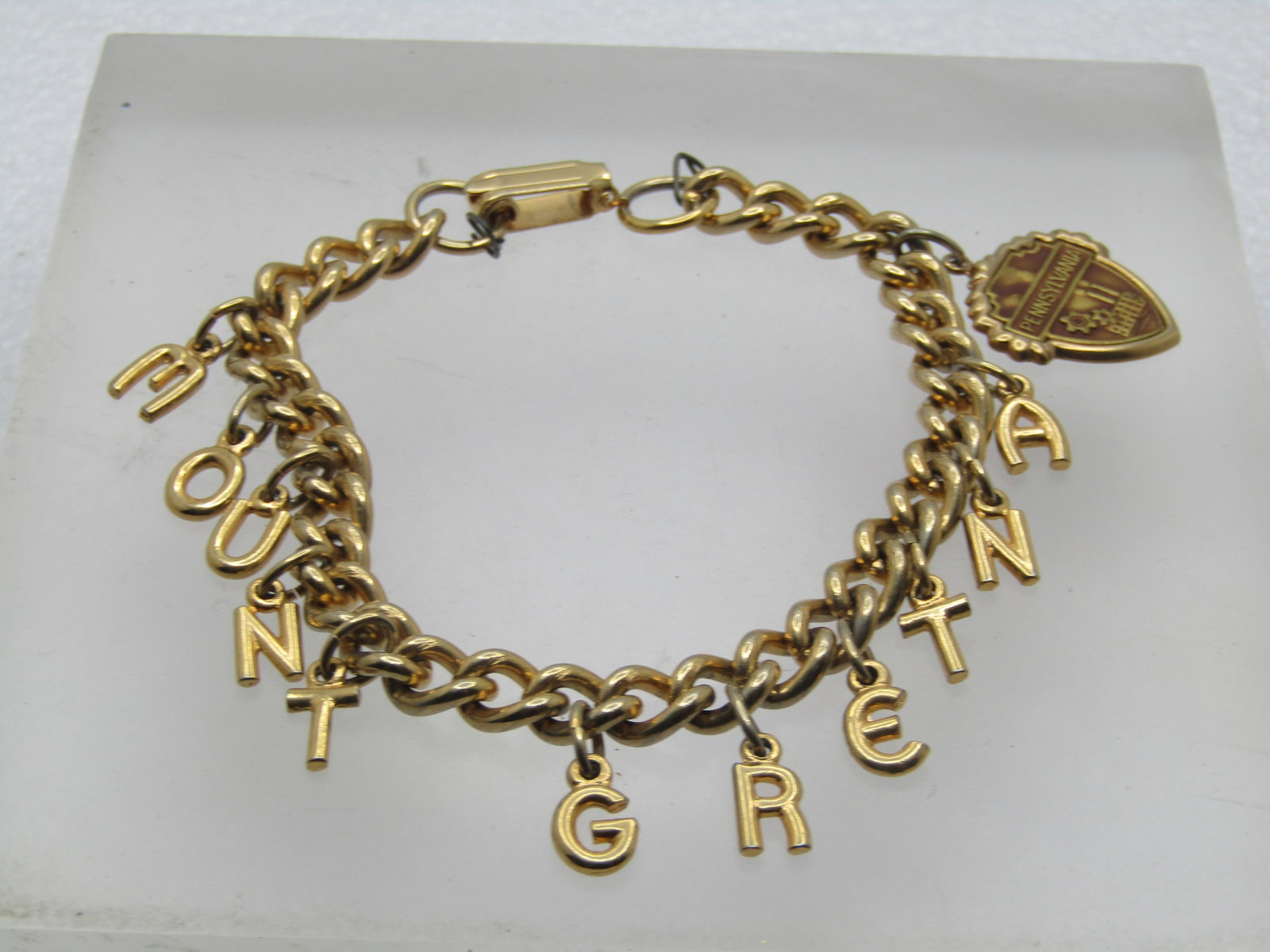 Vintage Mt. Gretna Charm Bracelet, Pennsylvania, 7", 1960's: Vintage Mt. Gretna Charm Bracelet, Pennsylvania, 7". 1960's. Gold tone letters spelling out Mount Gretna with a Pennsylvania charm with a factory and gears in the shape of a shield. It is appx. 7" Lon