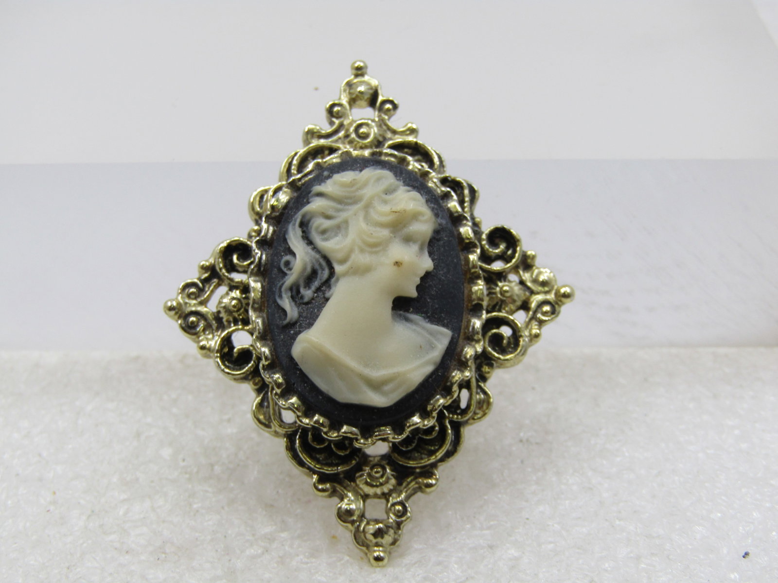 Vintage Black & White Cameo, Diamond Shaped, 1960's, Signed Gerry's: Vintage Black & White Cameo, Diamond Shaped, 1960's, Signed Gerry's. It is gold tone and diamoned shaped with a scrolled ornate frame. The brooch is appx. 2" tall by 1.5". Signed Gerry's. Very good co