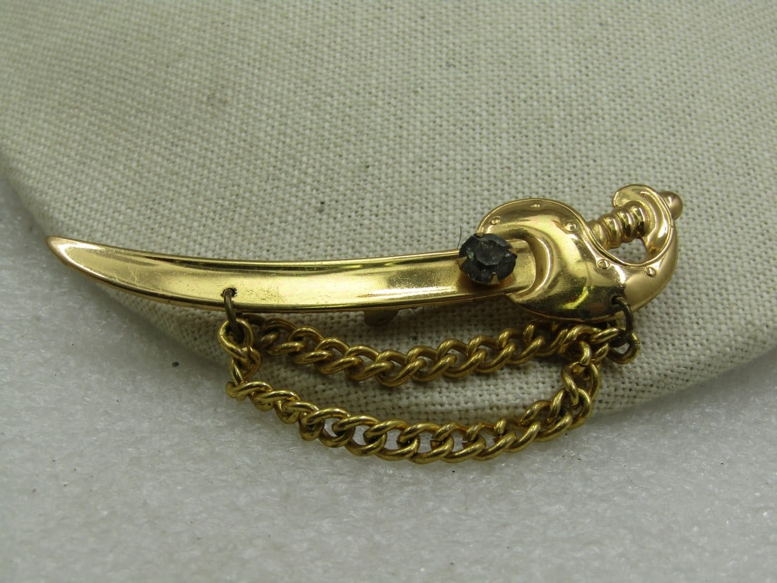 Vintage Coro Sword With Chain Brooch, Smoky Rhinestone, Mid-Century: Vintage Coro Sword With Chain Brooch, Smoky Rhinestone, Mid-Century. This is gold tone with a double drape of curb link chain that hangs down from the sword. The chain is appx. 5mm wide. The sword is