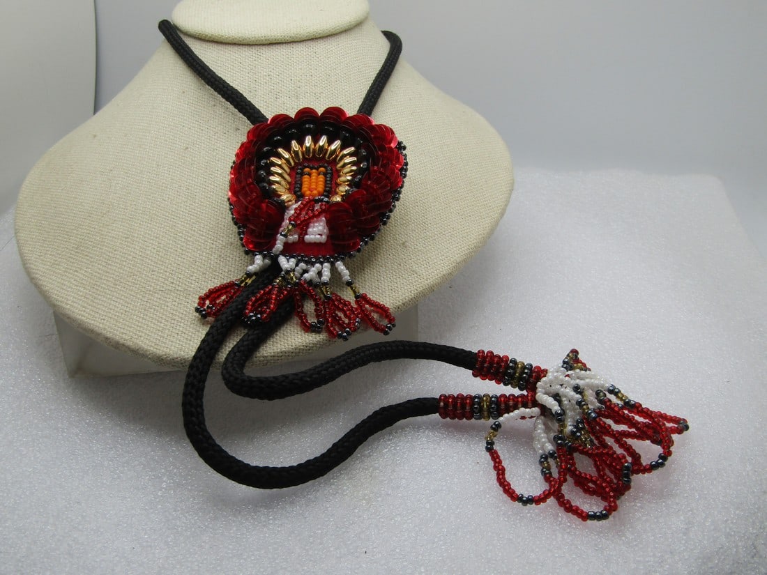 Vintage Beaded/Sequins Chief Bolo Tie, Dark Orange/White/Red/Black, 32" with Tassels, 1970's-1980's: Vintage Beaded/Sequins Chief Bolo Tie, Dark Orange/White/Red/Black, 32" with Tassels, 1970's-1980's. This has a glass seed beaded Native American Chief with large orange sequin headdress and faux gold