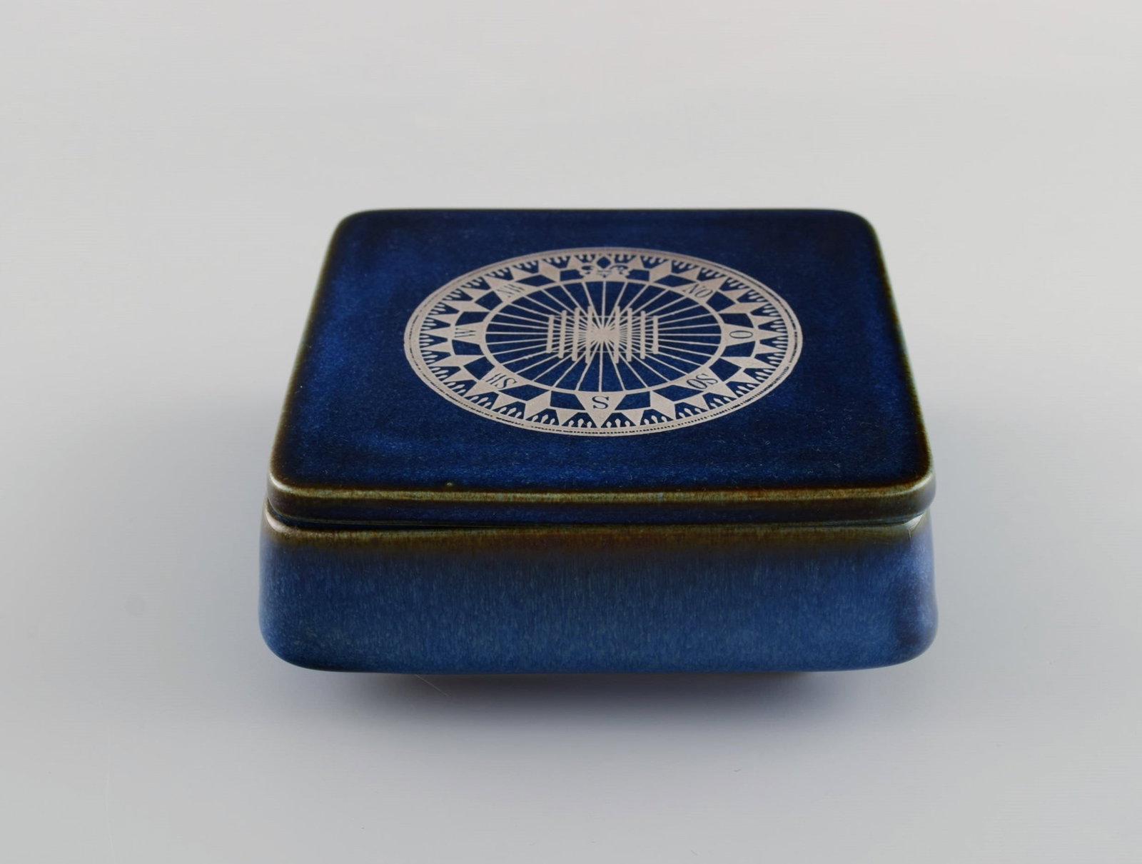 Sven Jonson (1919-1989) Gustavsberg. Lagun lidded box in glazed stoneware with silver inlay in the: Sven Jonson (1919-1989) Gustavsberg. Lagun lidded box in glazed stoneware with silver inlay in the form of a compass. Beautiful glaze in shades of blue. 1970s. Measures: 14 x 14 x 5.5 cm. In excellent
