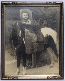 A photo of a young boy in Western costume on a pony