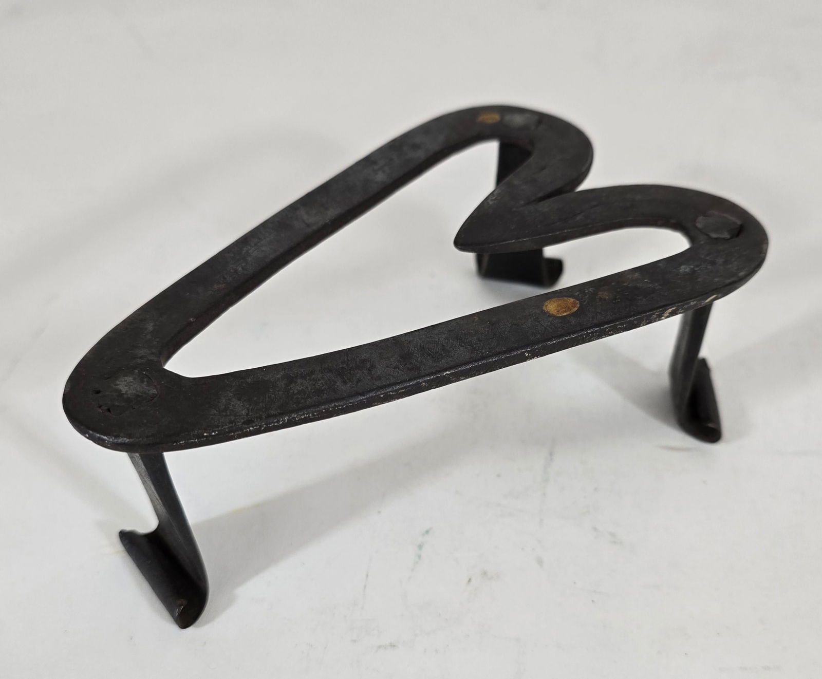 Heart form trivet: Title: Heart form trivet Dimension: 6 x 4 x 2.5 high Description: Early 19th century wrought iron heart form trivet with unusual curled feet. A good form. Shipping: Domestic: Flat-rate of $15.00 to an