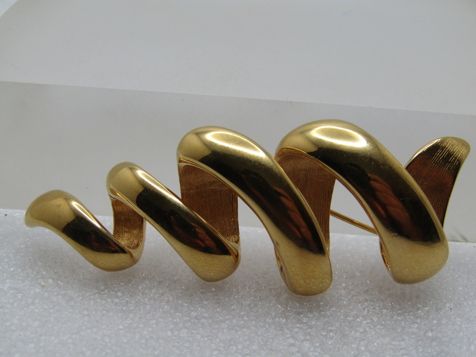 Vintage Monet Spiral Scribble Brooch, 1980's, Mod: Vintage Monet Spiral Scribble Brooch, 1980's, Mod Design with a 3-D type of sprial scribble that is gold tone and appx. 2.75" tall and 1" wide Smoth and shiny on the top surface with a textured finish