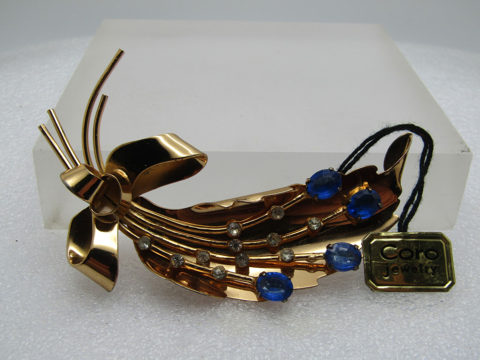Vintage Coro Pegasus Rhinestone Brooch, With Tags, Leaf, Blue/Clear, 1950's-1960's: Vintage Coro Pegasus Rhinestone Brooch, With Tags, Leaf, Blue/Clear, 1950's-1960's. Thsi is a curved leaf with bow that has four stems of clear and blue rhinestones in the center of the leaf. Gold ton