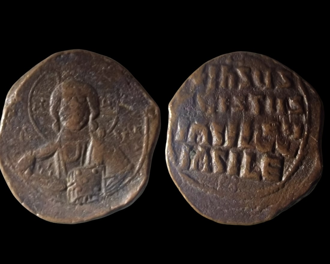 The Byzantine Empire: Byzantine Bronze Follis featuring Christ (10th-11th Century). This historical coin showcases a portrait of Christ on the obverse, encircled by a halo, with the reverse inscription 'IHXUS XRISTUS BASIL