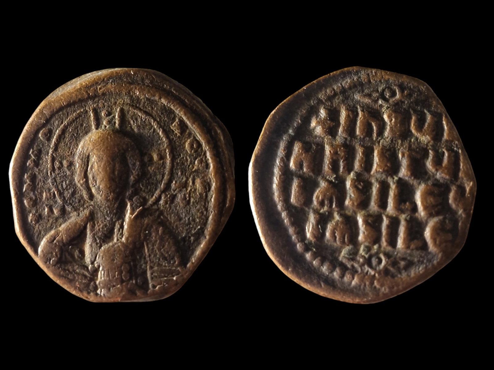 The Byzantine Empire: Byzantine Bronze Follis depicting Christ (10th-11th Century). The obverse features a portrait of Christ with a halo, raising his hand in blessing, a common motif in Byzantine religious coinage. The re