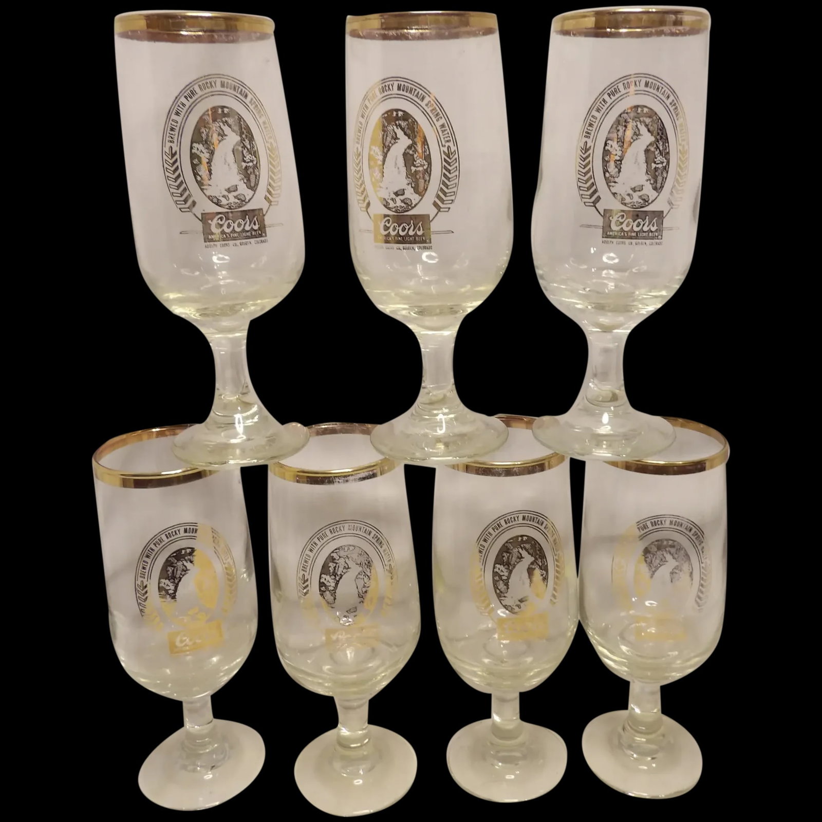 Vintage Coors Gold Label Stemmed Pilsner Beer Glasses: This set of 7 Vintage Coors Gold Label Stemmed Pilsner Beer Glasses (have some visible loss of gold around rim) have logos in great condition. They stand 7 1/8 inches tall and hold approximately 12 oz