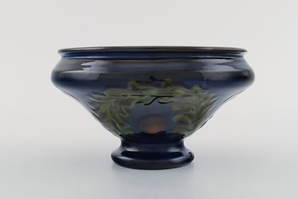 Kähler, Denmark. Bowl in glazed ceramics. Green leaves and red berries on a dark blue