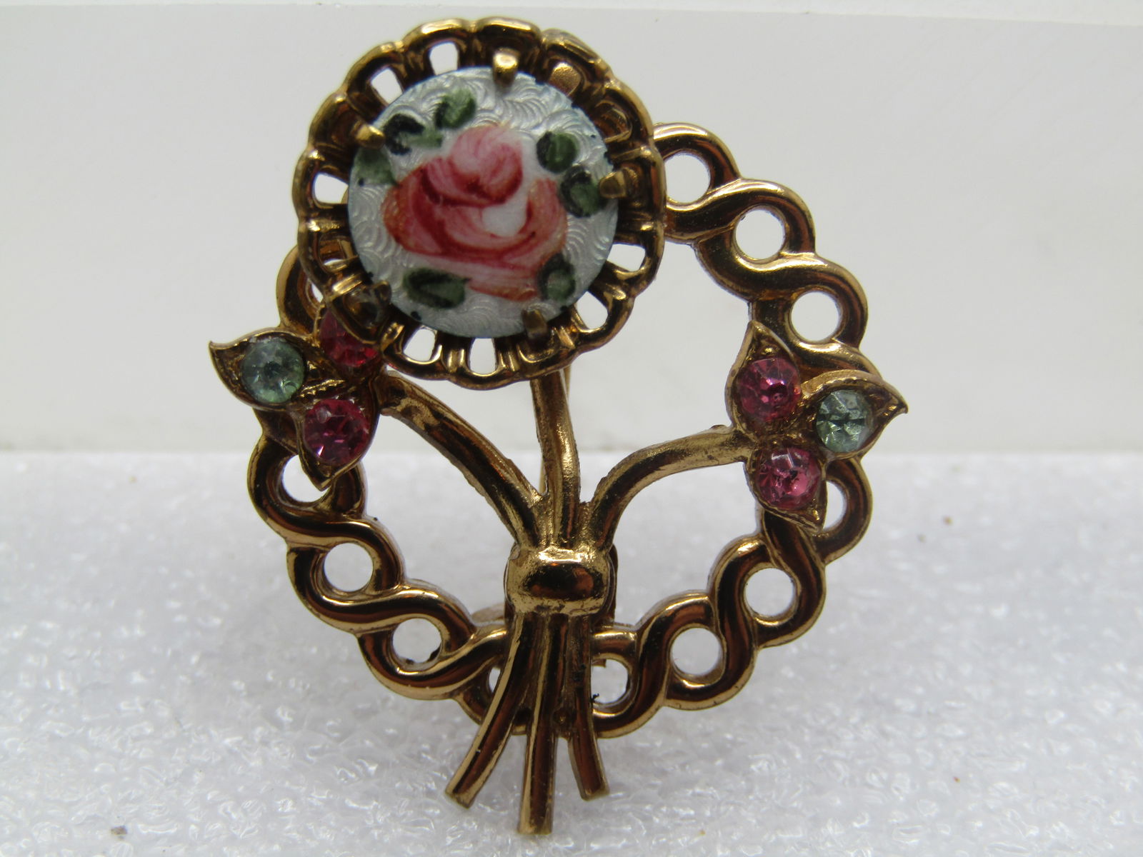 Vintage Guilloche Rose & Rhinestone Brooch, 1960's: Vintage Guilloche Rose & Rhinestone Brooch, 1960's. Gold tone with an open circle design and a floral stem covering the center of the brooch and rhinestone pink and blue leaves resting on the circle w