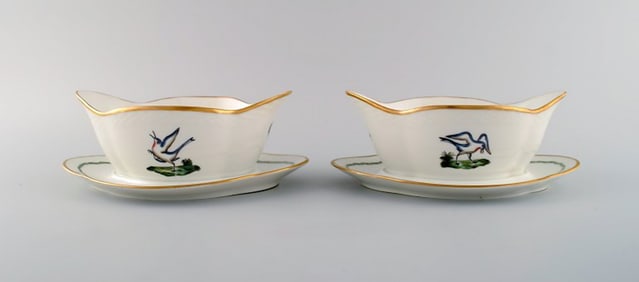 Two Royal Copenhagen sauce boats in hand-painted porcelain with bird motifs and gold decoration.