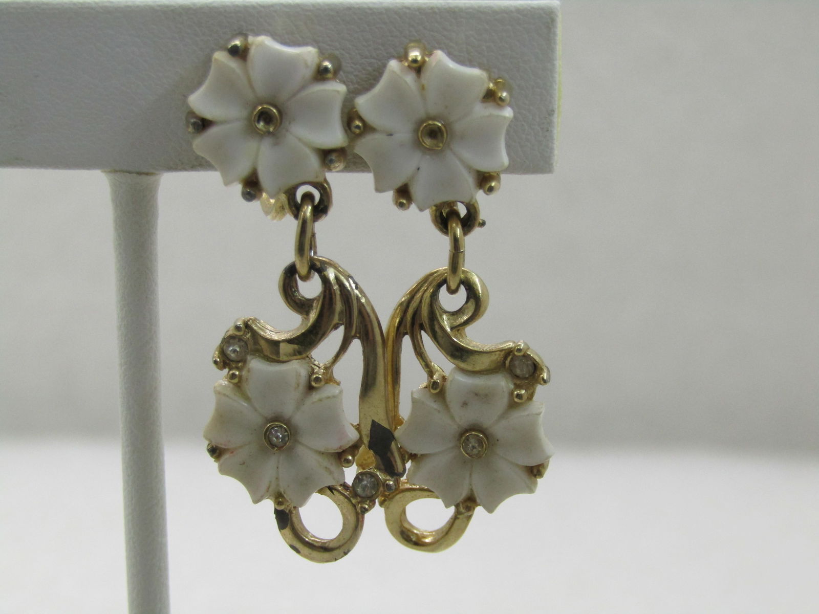 Vintage White Forget-Me-Not Rhinestone Earrings, Stud and Drop, 1.75", 1960's-1970's: Vintage White Forget-Me-Not Rhinestone Earrings, Stud and Drop, 1.75", 1960's-1970's. A white plastic blossom in the stud and dangle with rhinestone accents. Gold tone with vine and stem like accents.