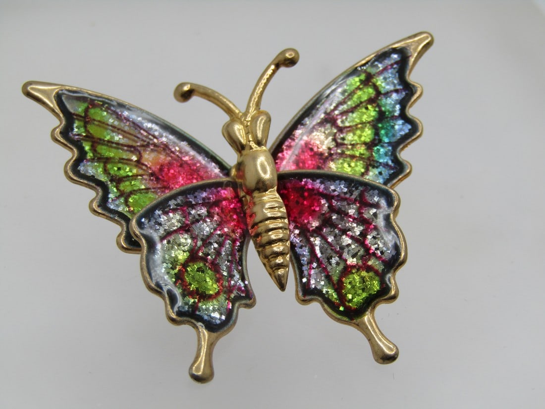 Vintage Colorful Glittery Butterfly Brooch, 1960's-1970's: Vintage Colorful Glittery Butterfly Brooch, 1960's-1970's. Rainbow shimmery colors in the wings of thise butterfly with black outlines. Gold tone torso. It is appx. 1.75" wide and 1.5" tall. C-clasp. 