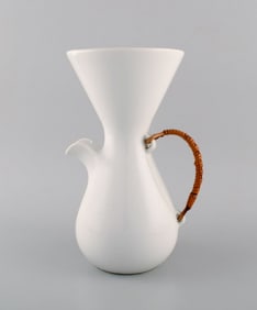 Freeman Lederman. Large modernist jug in white glazed ceramics with wicker handle. Mid-20th century.
