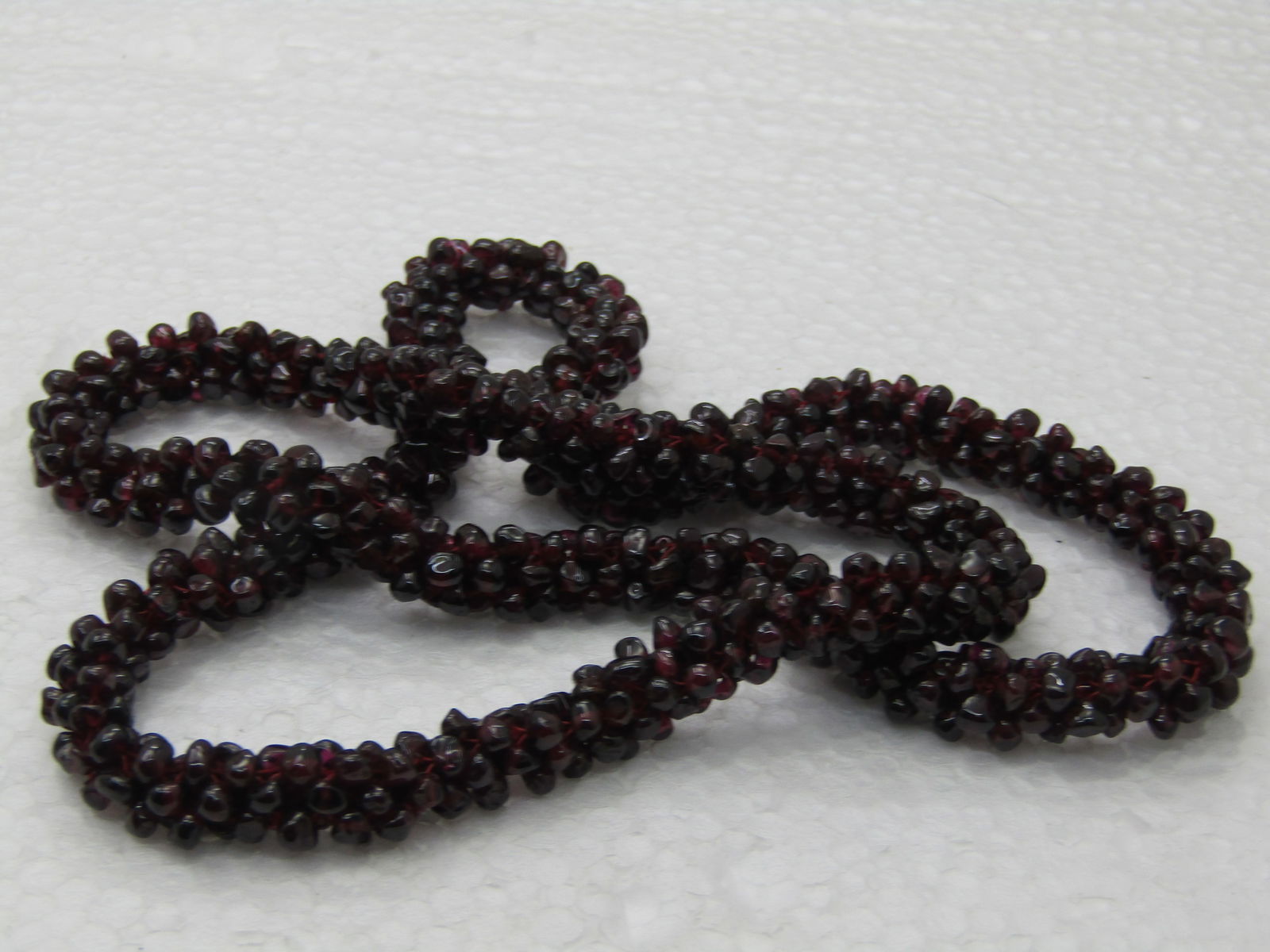 Stauer Garnet Beaded Garland Necklace, 24", 9mm wide, in Blue Pouch: Stauer Garnet Beaded Garland Necklace, 24", 9mm wide, in Blue Pouch. Small polished garnet beads in a round thick woven strand creating a garland to slipover your head. 24". In Blue Stauer pouch, Age