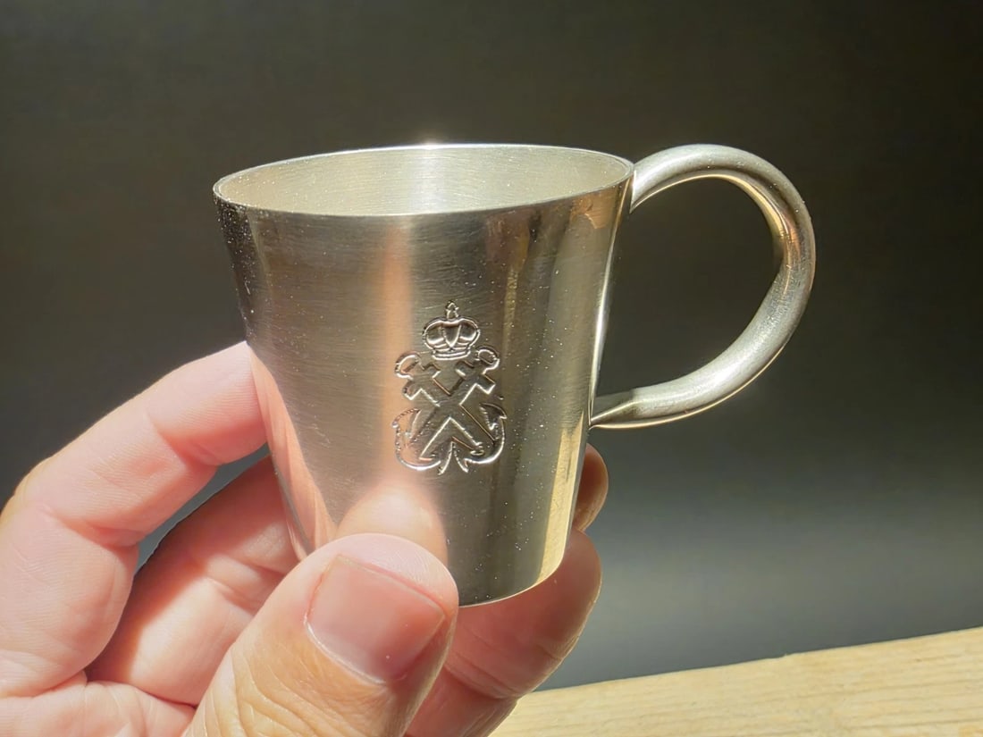 Metal Royal Navy Rum Cup Shot Glass Mug: Wonderful reproduction royal navy rum cup. It features a handle and an engraved emblem on the side. The emblem appears to be a crowned symbol with crossed anchors, resembling a royal or naval cypher. 