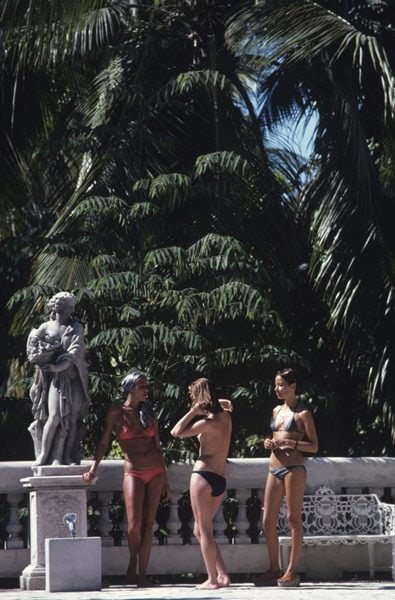 Slim Aarons 'Bikinis In Haiti' 1975 Oversize Unframed C Type Print: Description Slim Aarons 'Bikinis In Haiti' 1975 Oversize Unframed c type print Marni Morrell and Denise Schluscer with a third woman, all wearing bikinis, pose beside a statue on a bridge in Haiti, in