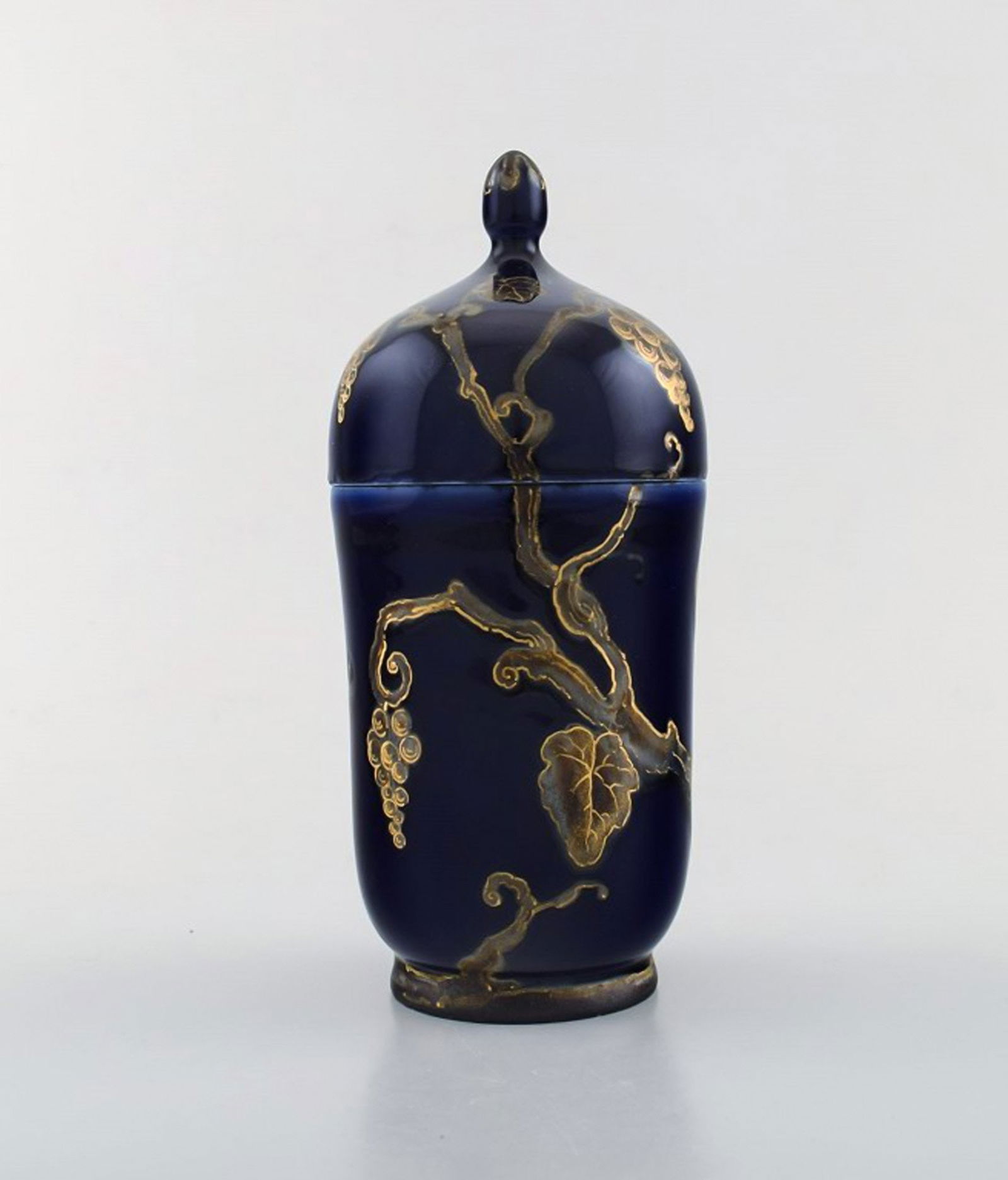Karl Lindström and Nils Emil Lundström for Rörstrand. Lidded porcelain jar decorated: Karl Lindström and Nils Emil Lundström for Rörstrand. Lidded porcelain jar decorated with grape vines in gold on beautiful dark blue base. Japanism, ca. 1920. In very good condition. Me