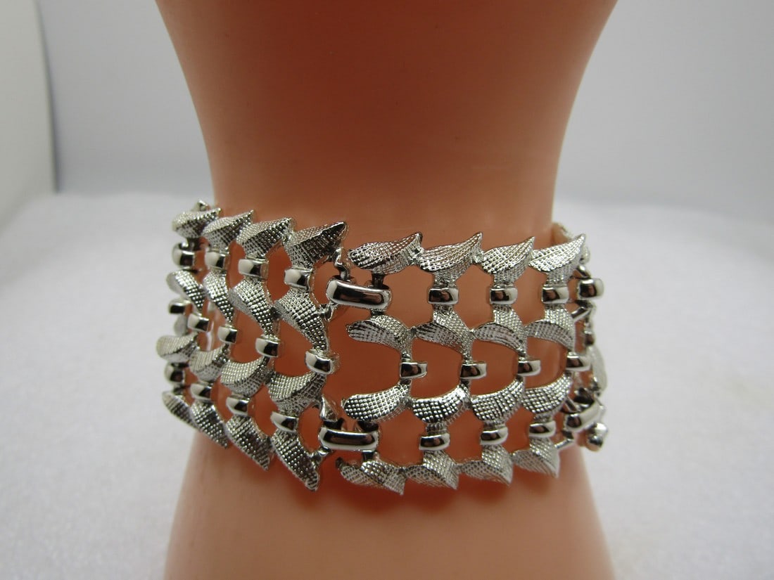 Vintage Coro Signed Wide Bracelet, 7.25" Silver Tone, 1960's: Vintage Coro Signed Wide Bracelet, 7.25" Silver Tone, 1960's. Silver tone bracelet with a textured curved design with smooth accents on the curved bow-like shapes. It is appx. 1.25" wide and 7.25" wid