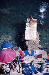 Porto Ercole' Slim Aarons: Description Porto Ercole 1980 Photo by Slim Aarons A jetty juts out from a rocky shoreline in Porto Ercole, Tuscany, August 1980 Open Edition C type print Archive Stamped Comes with certificate of