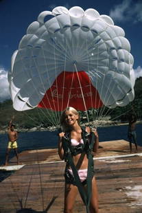 Slim Aarons 'Paraglider' 1968 C Type Print Framed In Black: Description Slim Aarons 'Paraglider' 1968 C Type Print Framed In Black Preparing to go paragliding in Acapulco a young blonde woman holds on firmly to her parachute harness. 1968 (Photo by Slim